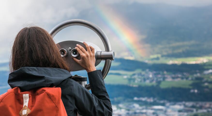 Woman looking through tower viewer at a rainbow