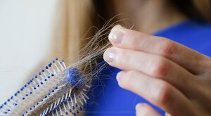 Close-up woman holding cleans brush filled with hair