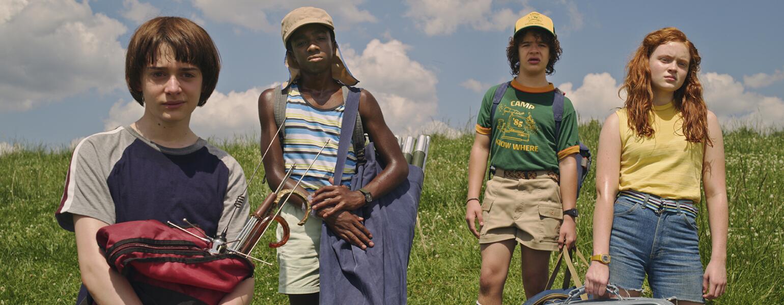 Awesome TV shows Stranger Things cast in a field from season 3