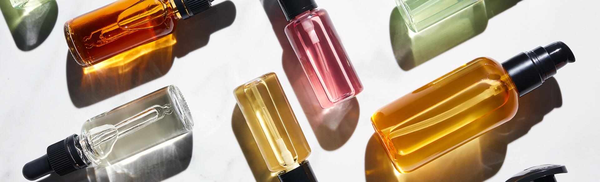Different Bottles Of Colorful Liquids On White.
