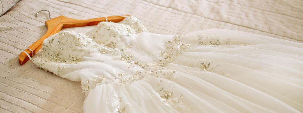 White wedding dress laying on a bed