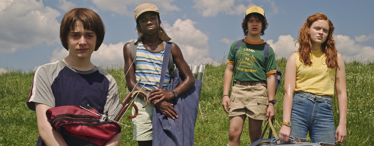 Awesome TV shows Stranger Things cast in a field from season 3