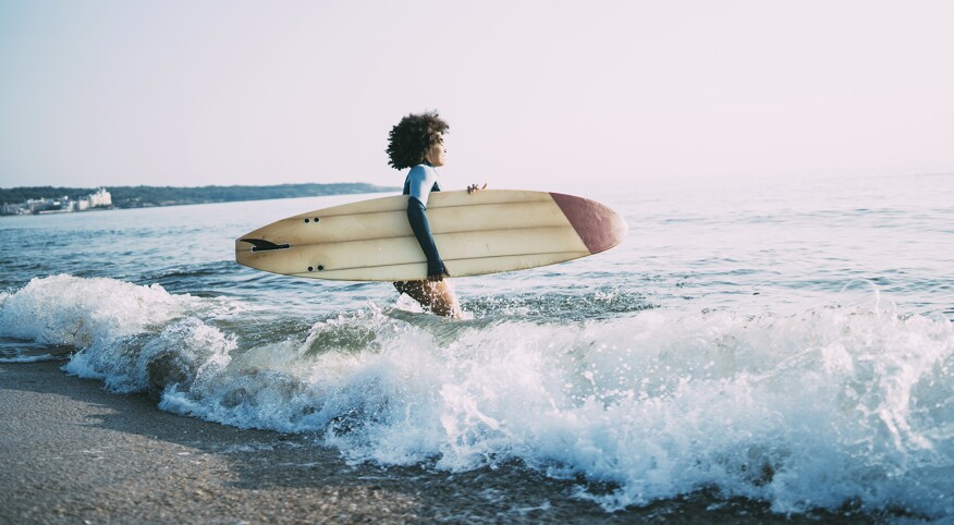 photo_of_african_american_woman_walking_in_ocean_with_surfboard_Surfing_GettyImages-1013089202_1540