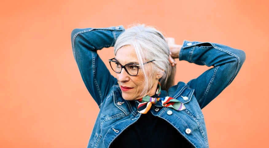Mature woman pulling back her silver hair into a ponytail