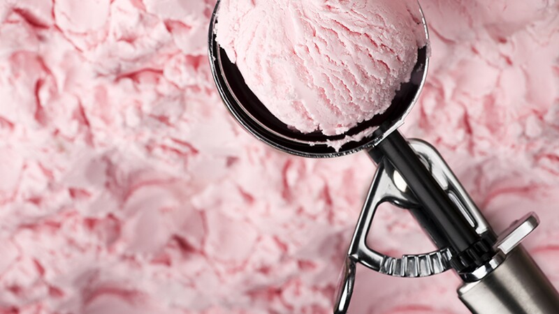 A close-up view of strawberry ice cream in a scooper