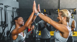 High angle view of happy girlfriends giving high five in gym