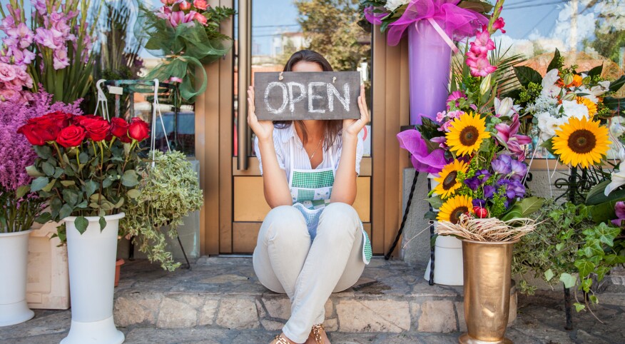 Florist Sitting In Front Of Her Shop.