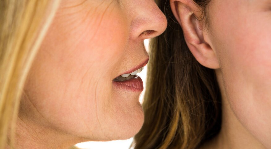 Mother whispering something to her daughter