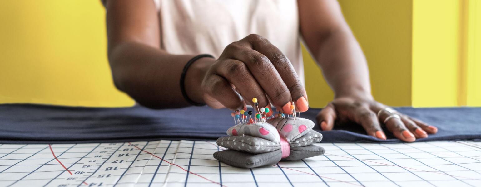 Woman Seamstress adjusting a garment on yellow background