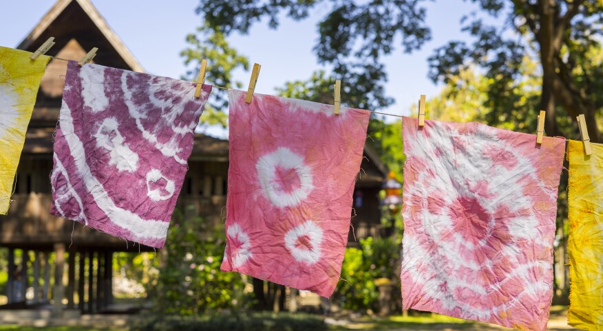 Colorful abstract tie dyed fabric hung up to dry on clothesline