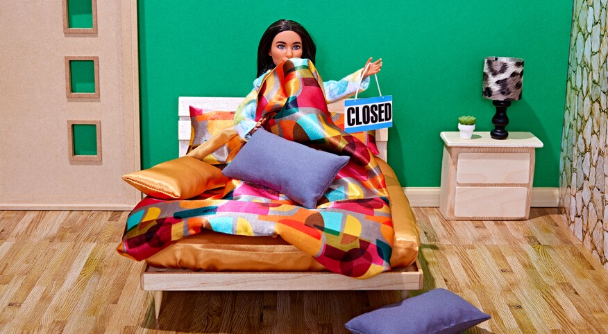 Doll on a bed holding a closed sign