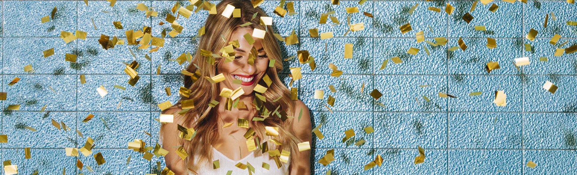 Single woman smiling with confetti falling down around her