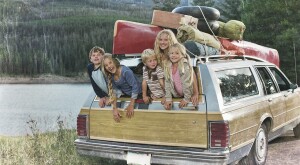 Vintage setting of station wagon car packed with vacation gear and the kids are hanging out of the back window