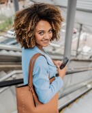 woman looking over her shoulder with large brown purse