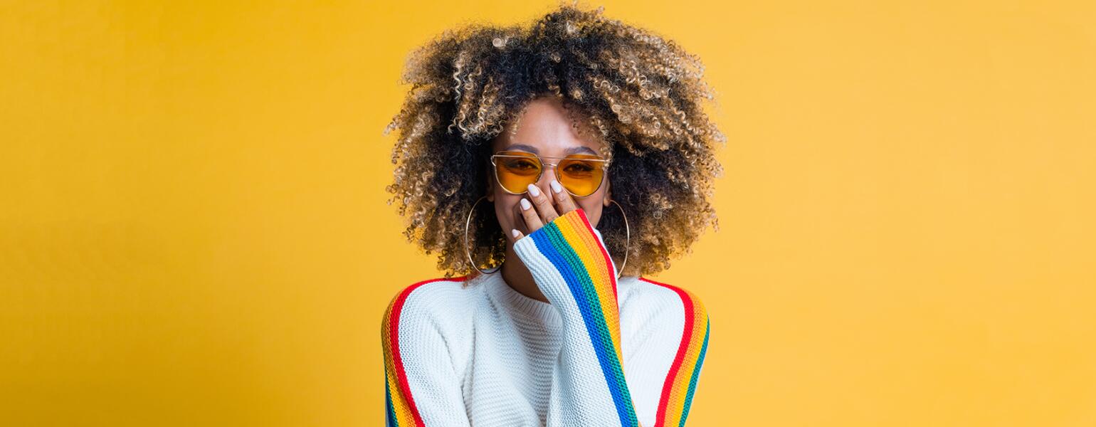Surprised afro girl standing against yellow background showing her beautiful curls