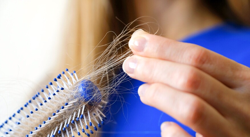 Close-up woman holding cleans brush filled with hair