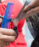 The hairdresser arranges the hair of her client by cutting them with scissors.