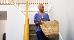 Woman walking down stairs with woven laundry basket