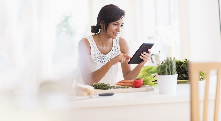 Hispanic woman cooking with digital tablet