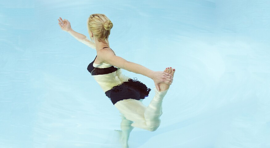 Mid adult woman holding her foot while practicing yoga in a swimming pool