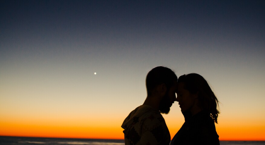 couple embracing in front of sunset