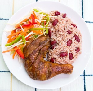Caribbean style jerk chicken served with rice mixed with red kidney beans. Dish accompanied with vegetable salad. Shallow DOF.