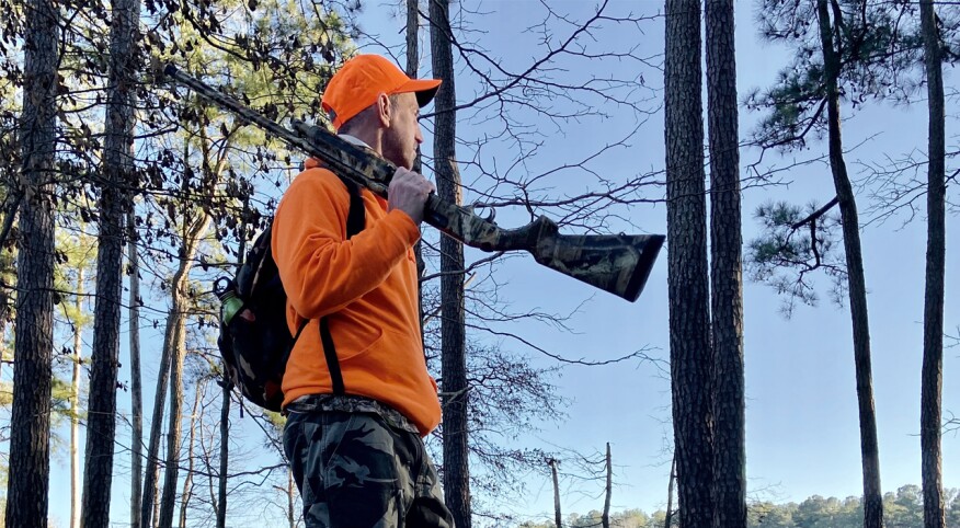 Man in orange hunting and holding a rifle