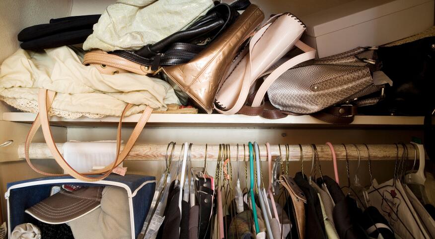 cluttered closet full of clothes and purses