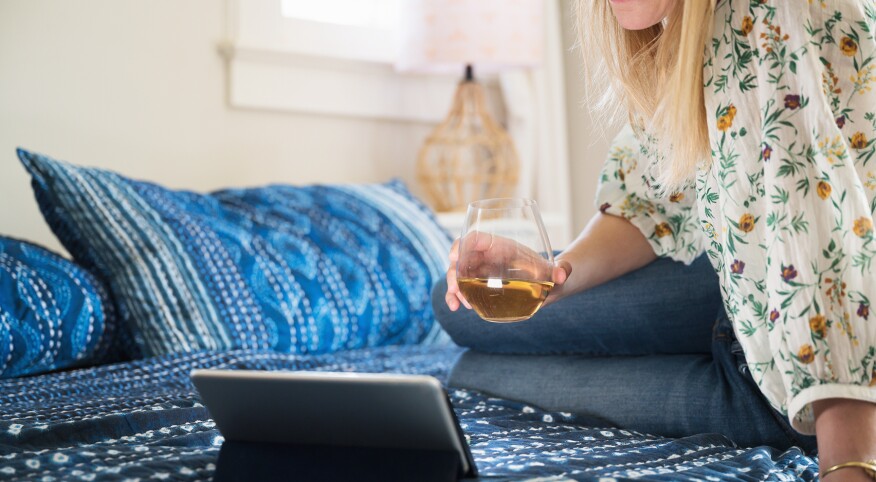 Woman With Glass Of Wine Using Tablet To Chat