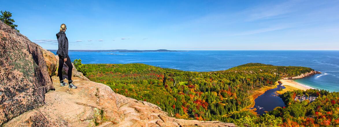 Hiker enjoying the panoramic view from the top of Beehive Trail in Acadia National Park