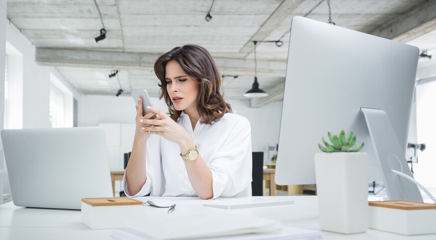 woman at work looking at her phone upset