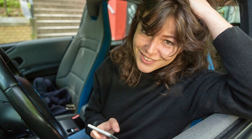 Portrait smiling young woman using smart phone in car