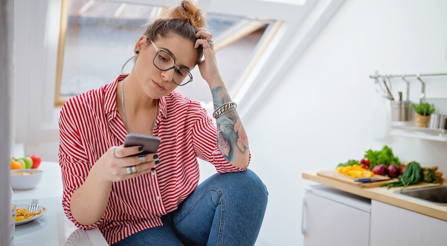 woman who is upset looking at phone after seeing her ex husband unfriended her on facebook