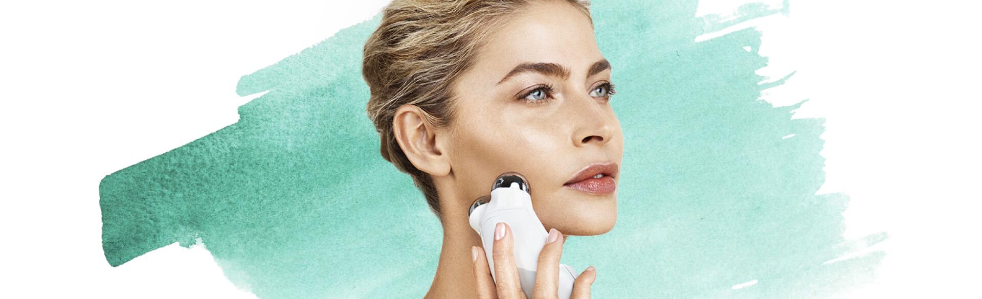 woman using face massager to tighten her skin