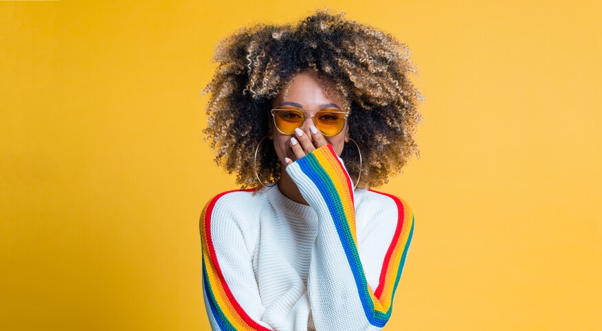 Surprised afro girl standing against yellow background showing her beautiful curls