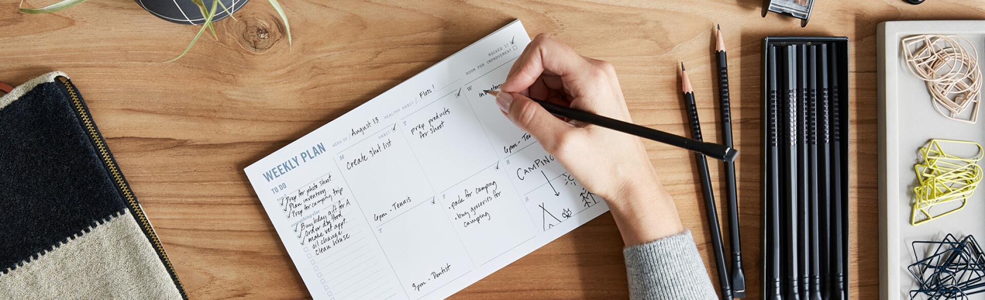 Overhead Shot Of A Small Business Owner Writing In Weekly Planner