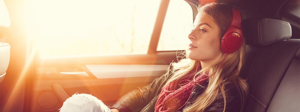 Woman sitting in the back seat of an Uber with headphones on