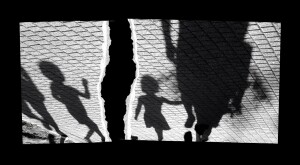 Blurry shadow of a little boy and a girl walking with adults on park pavement in black and white