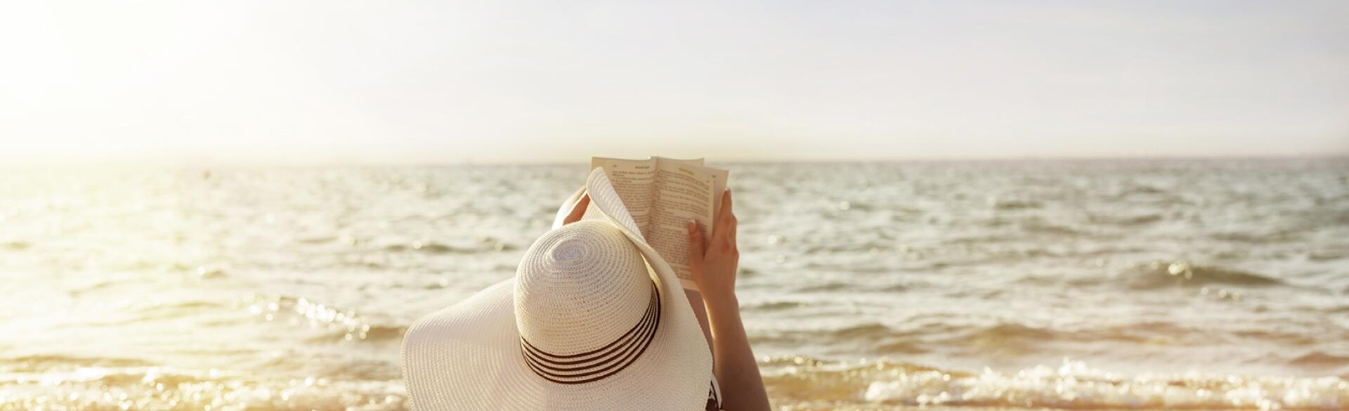 woman laying on towel reading on beach in the sun
