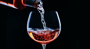 High contrast bottle of wine being poured into a glass with black background