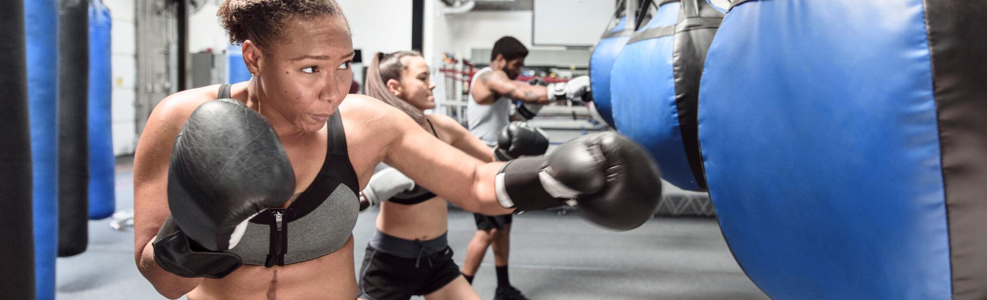 Woman hitting a blue punching bag with black boxing gloves