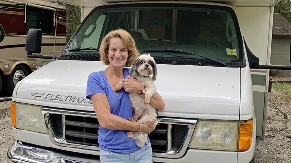 Michelle Fishburne holding her dog, Buddy, in front of her RV