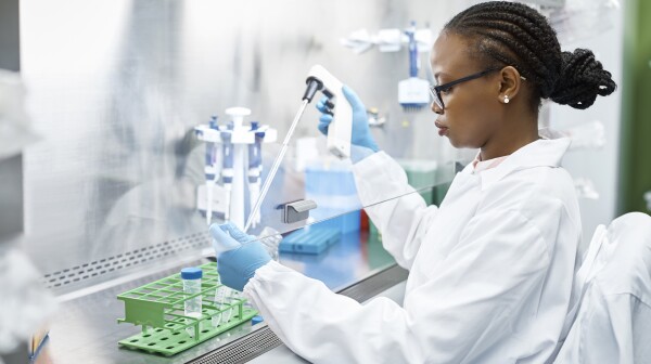 Female scientist analyzing medical sample in test tube. Young researcher is wearing lab coat. She is concentrating while working in laboratory.