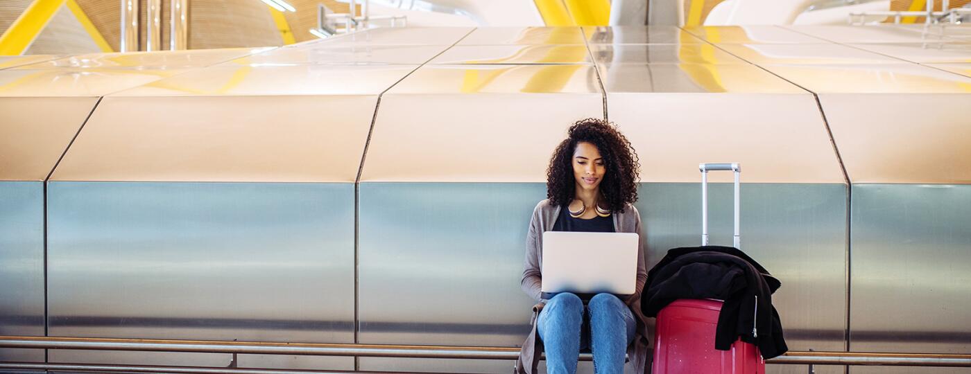 attractive black Woman at the airport sitting and working with laptop