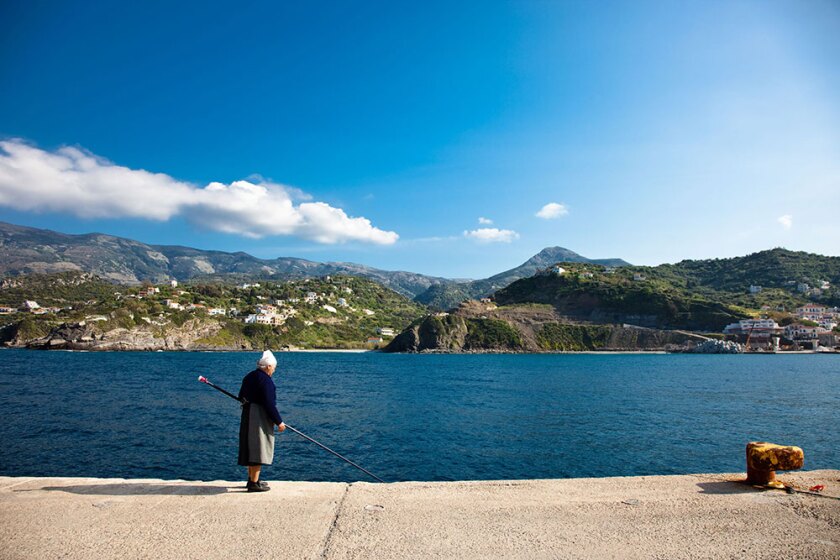Woman walks along the water in Ikaria, Greece