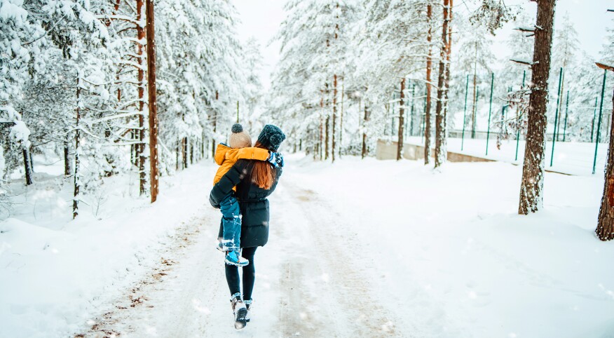 View from backside of mother carrying child through a snowy trail