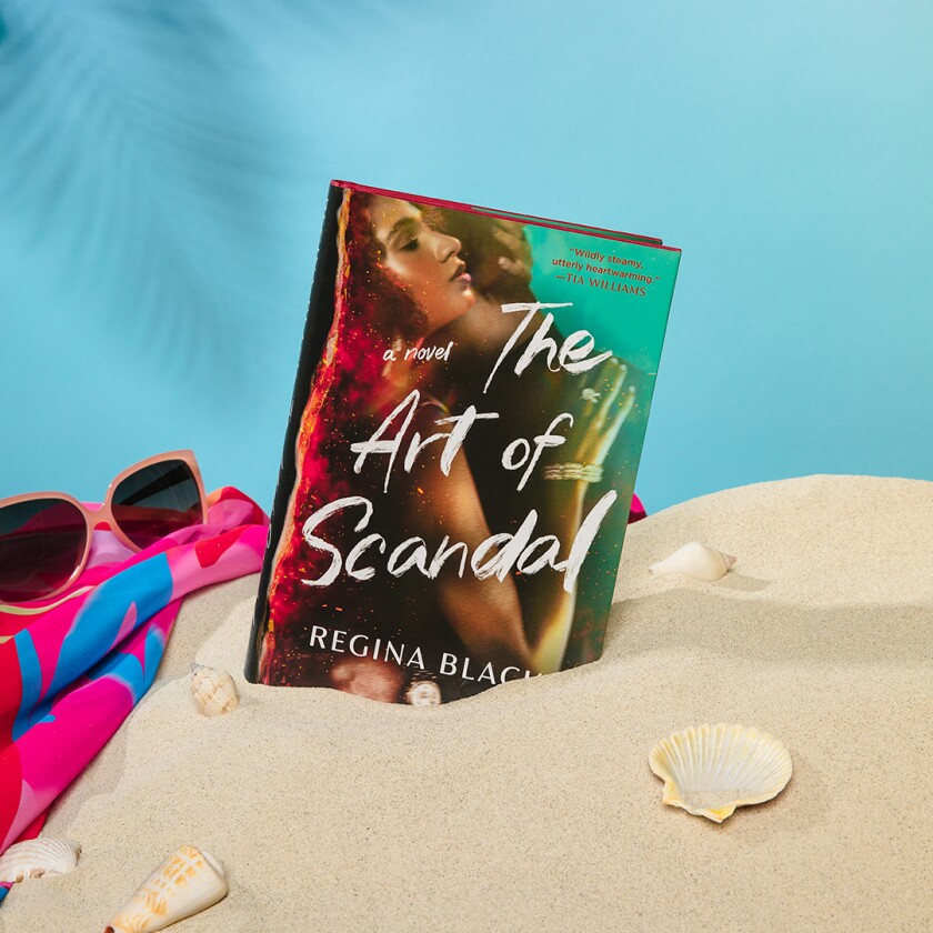 Book styled in pile of sand with beach accessories