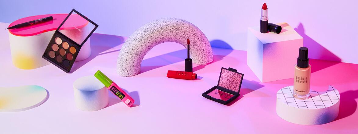 Makeup products styled on a neon purple and pink background