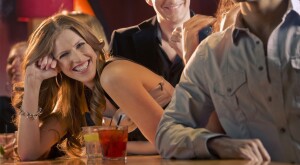 Woman at bar with drinks, smiling 