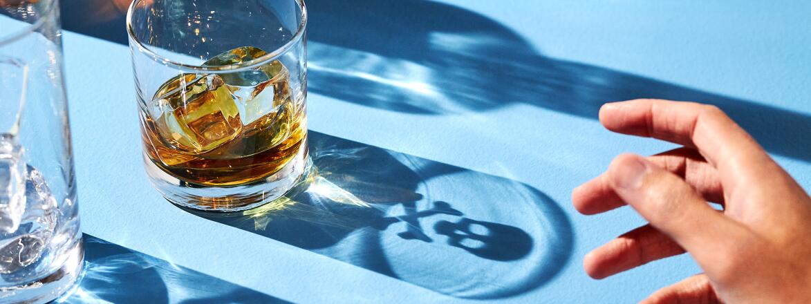 Hand reaching out to alcohol drink with shadow of skull and cross bones
